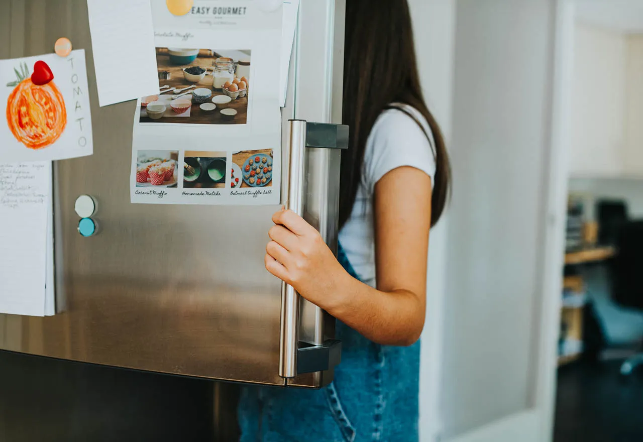 girl picking something to eat out of the fridge